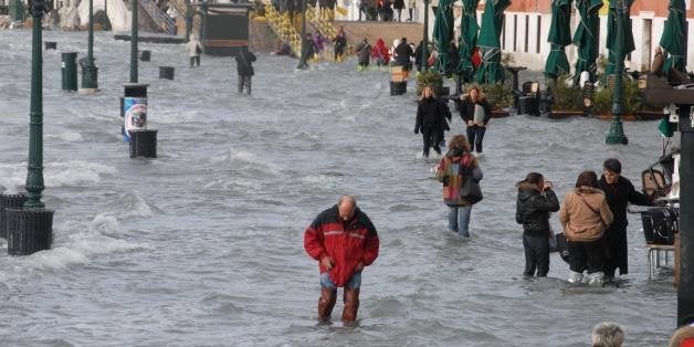 People walk on a flooded quay of the Grand canal of Venice on December 1, 2008. Authorities in the Italian city of Venice issued a flood alert, warning that the sea was due to rise 1.60 metres above its normal level, the highest for 30 years. AFP PHOTO / ANDREA PATTARO (Photo credit should read ANDREA PATTARO/AFP/Getty Images)