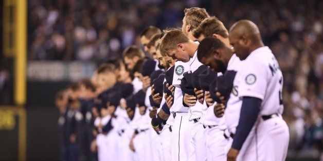 The Seattle Mariners bow their heads for a moment of silence in remembrance of the Oso mudslide victims prior to the team's home opener against the Los Angeles Angels at Safeco Field in Seattle on Tuesday, April 8, 2014. (Thomas Soerenes/Tacoma News Tribune/MCT via Getty Images)