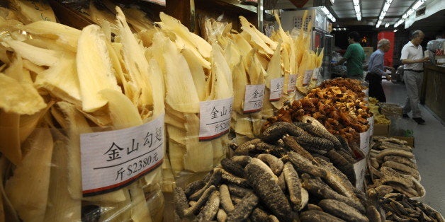 People shop as shark fins (L) are displayed for sale in Hong Kong's Shueng Wan district on March 21, 2010. China, Japan and Russia have helped defeat a proposal at a UN wildlife trade meeting held on March 17 that would have boosted conservation efforts for sharks. According to studies of the shark fin market, up to 73 million sharks are killed each year, primarily for their fins used in shark fin soup. A bowl of shark fin soup can cost 100 USD, with a single fin being worth more than 1,300 USD. AFP PHOTO / Dale de la Rey (Photo credit should read DALE de la REY/AFP/Getty Images)