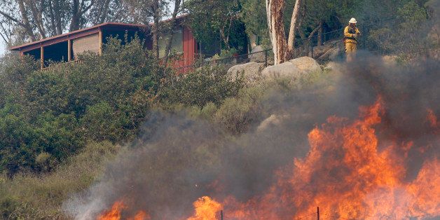SAN MARCOS, CA - MAY 15: Flames spread toward a house at the Cocos fire on May 15, 2014 in San Marcos, California. Fire agencies throughout the state are scrambling to prepare for what is expected to be a dangerous year of wildfires in this third year of extreme drought in California. (Photo by David McNew/Getty Images)