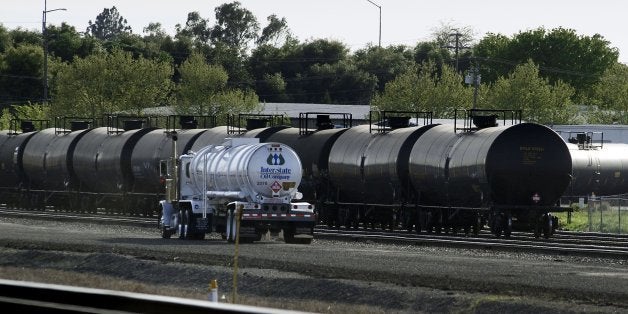 Recently filled, a tanker truck drives past railway cars containing crude oil on railroad tracks in McClellan Park in North H