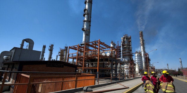 Firemen walk in front of one of the structures to refine oil at Mexican state-owned petroleum company PEMEX refinery in Tula, Hidalgo state, Mexico on March 8, 2011. AFP PHOTO/OMAR TORRES (Photo credit should read OMAR TORRES/AFP/Getty Images)