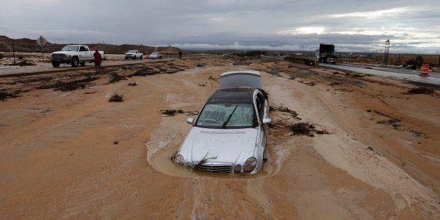 A car is partially buried in mud on Interstate 15 in Moapa, Nev., Monday, Sept. 8, 2014. The road is closed in both directions because of the flood damage. (AP Photo/John Locher)