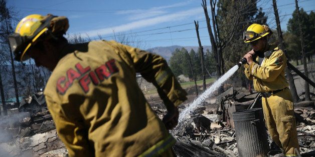 WEED, CA - SEPTEMBER 16: Firefighters mop up hot spots in the remains of a destroyed home on September 16, 2014 in Weed, California. A fast moving wildfire fueled by high winds ripped through the town of Weed on the afternoon of September 15, burning 100 structures including the high school and lumber mill. (Photo by Justin Sullivan/Getty Images)