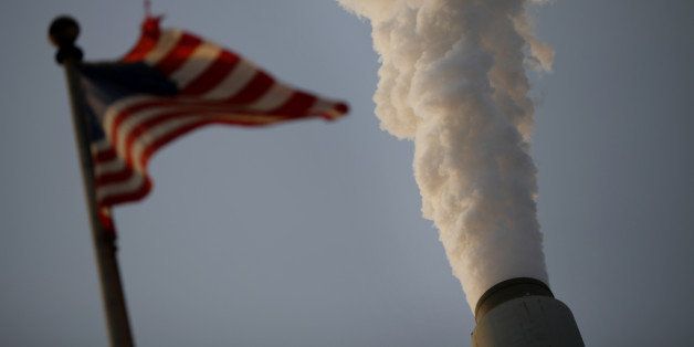 Emissions rise as a U.S. flag flies at the American Electric Power Co. Inc. coal-fired John E. Amos Power Plant in Winfield, West Virginia, U.S., on Thursday, July 31, 2014. Power plant coal burning by 2020 must decline by 204 million tons, or 24 percent, to meet U.S. Environmental Protection Agency (EPA) greenhouse gas targets announced June 2, Sanford C. Bernstein & Co. analysts led by Hugh Wynne estimated in a July 23 note to clients. Photographer: Luke Sharrett/Bloomberg via Getty Images
