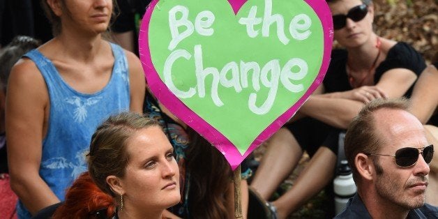 A climate protester holds up a placard at the G20 Finance Ministers and Central Bank Governors Meeting in Cairns on September 21, 2014. Finance ministers from G20 nations meet in Cairns this weekend as they grapple with how to achieve a lift in global growth by two percent while being held back by a sickly eurozone recovery. AFP PHOTO/William WEST (Photo credit should read WILLIAM WEST/AFP/Getty Images)