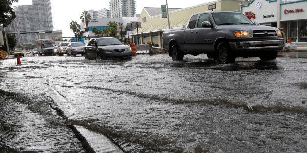 Vehicles negotiate heavily flooded streets as rain falls, Tuesday, Sept. 23, 2014, in Miami Beach, Fla. Certain neighborhoods regularly experience flooding during heavy rains and extreme high tides. New storm water pumps are currently being installed along the bay front in Miami Beach. National and regional climate change risk assessments have used the flooding to illustrate the Miami area's vulnerability to rising sea levels. (AP Photo/Lynne Sladky)