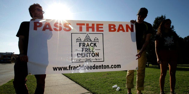 File - In this July 15, 2014 file photo, from left, Topher Jones, of Denton, Texas, Edward Hartmann, of Dallas and Angie Holliday of Denton, Texas, hold a campaign sign outside city hall, in Denton, Texas. Tensions are mounting as big oil companies and hydraulic fracturing opponents try to sway voters to their side over a Tuesday referendum that would make Denton the first Texas city to ban further permitting of the drilling practice known as fracking. (AP Photo/Tony Gutierrez, File)