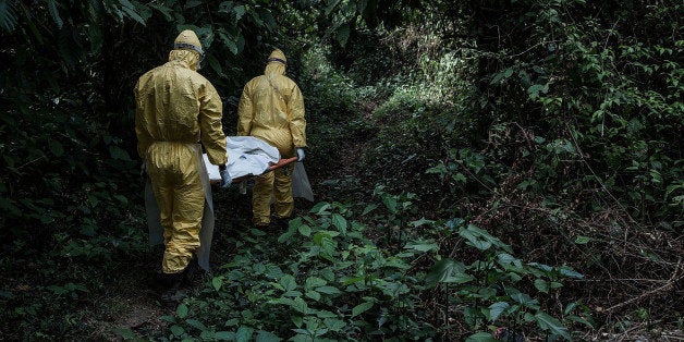 BO DISTRICT, SIERRA LEONE - MARCH 05: Healthcare workers in protective equipment bury a 13-year-old boy dying of Lassa fever at a specific location on March 5, 2014 in Bo district, Sierra Leone. In some parts of Sierra Leone, 10-16% of hospitalized patients have Lassa fever, an acute viral hemorrhagic fever endemic to parts of West Africa. Sierra Leone a high child mortality rate and in addition to this one of the highest maternal mortality rates in the world, with a maternal mortality rate (MMR) of around 890 deaths per 100, 000 live births. With the introduction of an ambulance referral system and access to 24-hour emergency obstetric care amongst other initiatives, MSF have managed to drastically reduce these deaths. Doctors Without Boarders (Médecins Sans Frontières) started the Gondama Referral Centre in collaboration with the Sierra Leone Ministry of Heath and offers free heath care to pregnant women and children under the age of 15. (Photo by Lam Yik Fei/Getty Images)