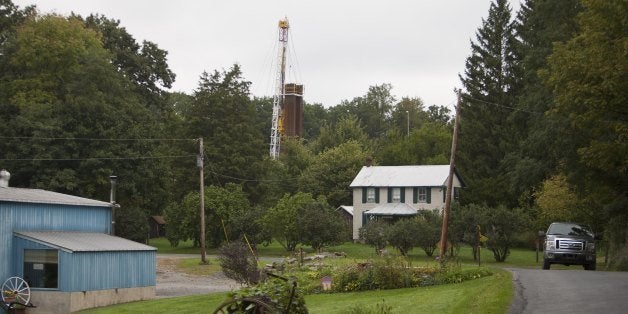 CALVERT, PA - SEPTEMBER 9: A car drives by a home with a nearby derrick drilling for natural gas near Calvert, Pennsylvania. The local area sits above the Marcellus Shale where debate occurs about drilling for natural gas and hydrofracking. Hydrofracking is a controversial drilling method which pumps millions of gallons of water, sand and chemicals into horizontally drilled wells to stimulate the release of the gas. The Marcellus Shale gas field stretches diagonally across West Virginia, Ohio, Pennsylvania and New York State. Drilling operations have provided Pennsylvania with billions of dollars of income through employment and tax revenue. The environmental impact is a politically sensitive issue in a resource dependent state. (Photo by Robert Nickelsberg/Getty Images)