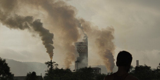 A man stands in front of a chemical factory as it discharges exhaust into the air of Mumbai, India, on Monday, Sept. 13, 2010. China and India are the biggest generators of UN carbon credits, which can be used to comply with pollution targets in the EU emissions trading system, the world's largest cap-and-trade program. Photographer: Dhiraj Singh/Bloomberg via Getty Images