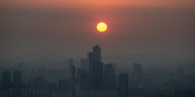 A photo taken at dusk on November 26, 2014 shows a general view of the skyline of Seoul shrouded in smog. Air quality monitors in Seoul recorded pollution levels of particulate matter 2.5 (PM 2.5) classed as 'unhealthy' on a scale defined by the US Environmental Protection Agency. AFP PHOTO / Ed Jones (Photo credit should read ED JONES/AFP/Getty Images)