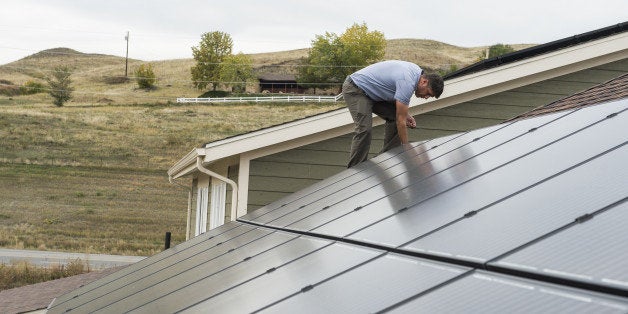 GOLDEN, CO - October 15: Joe Ostrowski cleans up around the side of one of the newly installed solar panels Wednesday, Octobe