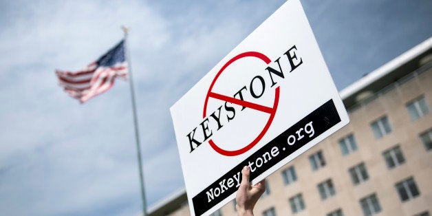 An activist holds up a sign outside the State Department during a protest of the Keystone XL pipeline on March 7, 2014 in Washington. Activists organized by the Energy Action Coalition marched to the State Department to protest the construction of the pipeline which would carry tar sands oil from Canada. AFP PHOTO/Brendan SMIALOWSKI (Photo credit should read BRENDAN SMIALOWSKI/AFP/Getty Images)