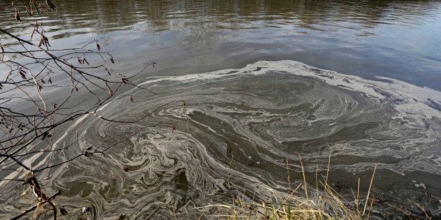 In this Wednesday, Feb. 5, 2014 file photo, signs of coal ash swirl in the water in the Dan River in Danville, Va. A year after the sudden collapse of an old drainage pipe triggered the third largest coal ash spill in U.S. history, regulators say they are still working to determine how much to fine Duke Energy, the nationâs largest electricity company. (AP Photo/Gerry Broome, File)