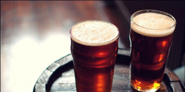 Two pints of beer bitter on wooden barrel in London pub.