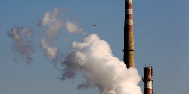 FILE - In this Nov. 13, 2014 file photo, a passenger airliner flies past steams emitted from a coal-fired power plant in Beij