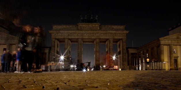 People gather around the Brandenburg Gate after the lights were turned off to mark Earth Hour in Berlin, Saturday, March 29,