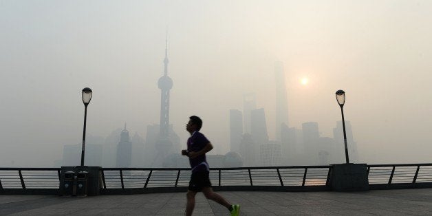 This photo taken on November 12, 2014 shows a resident exercising amid heavy smog on the Bund in Shanghai as the local meteorological department issued a yellow alert for smog. Chinese state media on November 13 sounded a note of caution on efforts to reduce carbon emissions, stressing 'orderly' progress after Beijing set a goal for its emissions to peak 'around 2030'. CHINA OUT AFP PHOTO (Photo credit should read STR/AFP/Getty Images)