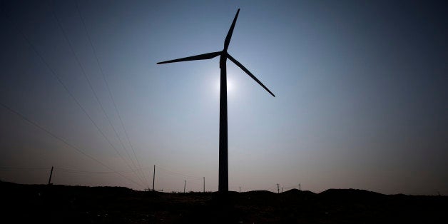 A wind turbine manufactured by DeWind Co. is silhouetted against the sun as it stands at a wind farm operated by EcoPower Co.