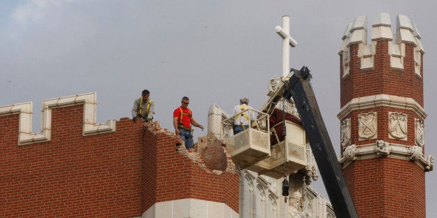 FILE - In this Nov. 6, 2011 file photo, maintenance workers inspect the damage to one of the spires on Benedictine Hall at St. Gregory's University following a magnitude-5.0 earthquake in Shawnee, Okla. New research suggests the quake, the sharpest to strike Oklahoma, may have been triggered in part by wastewater injection _ which, if true, would make the 2011 temblor the strongest ever linked to disposal practices within the oil and gas industry. (AP Photo/Sue Ogrocki, File)