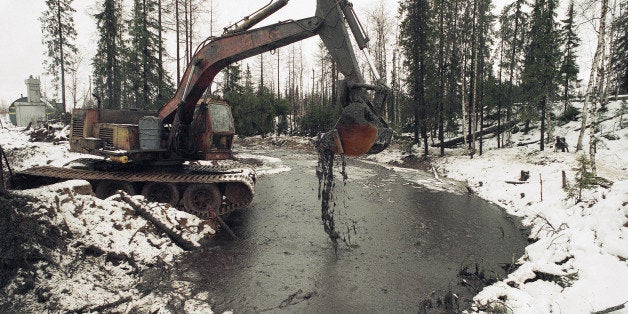 Heavy machinery is used to scoop up oily debris from the water s of a tributary of the Kolva River, some 27 miles north of th
