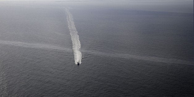 In this March 31, 2015 photo, a supply vessel crosses an oil sheen drifting from the site of the former Taylor Energy oil rig in the Gulf of Mexico, off the coast of Louisiana. The New Orleans-based company has downplayed the leak's environmental impact, likening it to scores of minor spills and natural seeps that the Gulf routinely absorbs. (AP Photo/Gerald Herbert)