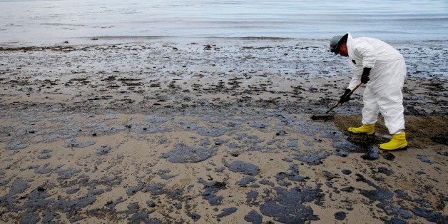 A worker removes oil from the beach at Refugio State Beach, north of Goleta, Calif., Thursday, May 21, 2015. More than 7,700 gallons of oil has been raked, skimmed and vacuumed from a spill that stretched across 9 miles of California coast, just a fraction of the sticky, stinking goo that escaped from a broken pipeline, officials said. (AP Photo/Jae C. Hong)