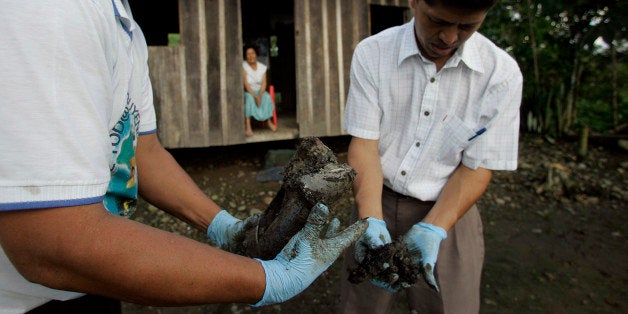 ** ADVANCE FOR SUNDAY, DEC. 21 ** Donald Moncayo, left, and Pablo Fajardo extract mud that contains oil from the yard of Mercedes Jimenez, behind, in Lago Agrio, Ecuador, Aug. 4, 2008. Ecuador's President Rafael Correa has sided squarely with the 30,000 plaintiffs, Indians and colonists, in a class-action suit, dubbed an Amazon Chernobyl by environmentalists, over the slow poisoning of a Rhode Island-sized expanse of rainforest with millions of gallons of oil and billions more of toxic wastewater. (AP Photo/Dolores Ochoa) ** NO ONLN ** NO IONLN **