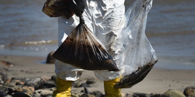 Workers clean oil from the rocks and beach at Refugio State Beach in Goleta, California, May 22, 2015. The oil company behind a crude spill on the California coast vowed to do the 'right thing' to clear up the mess, even as reports emerged of past leaks involving its pipelines. Plains All American Pipeline made the pledge as it said nearly 8,000 gallons of oil had been scooped up, out of some 21,000 gallons believed to have flooded into the ocean near Santa Barbara, northwest of Los Angeles. AFP PHOTO/ MARK RALSTON (Photo credit should read MARK RALSTON/AFP/Getty Images)