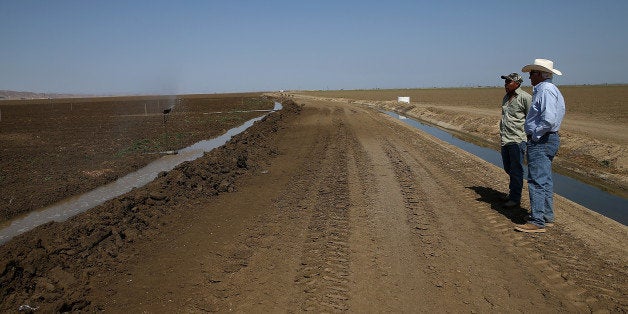 FIREBAUGH, CA - APRIL 23: Farmer Joe Del Bosque (R) talks with a worker as they irrigate a field on April 23, 2015 in Fireba