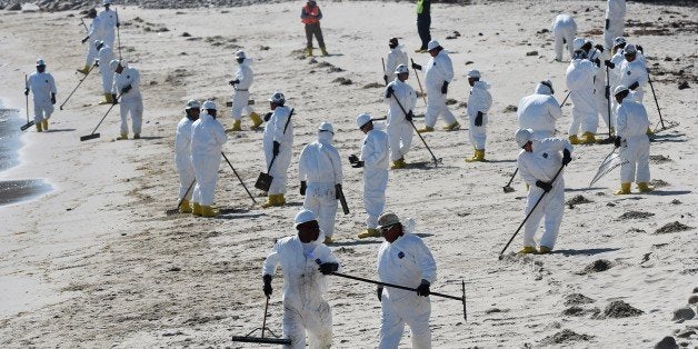 Workers clean oil from the rocks and beach near Refugio State Beach in Goleta, California, May 22, 2015. The oil company behi