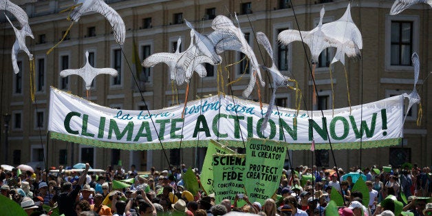 People hold a banner reading ' Climate action Now ' in St. Peter's Square, at the Vatican, Sunday, June 28, 2015. Greeting pe