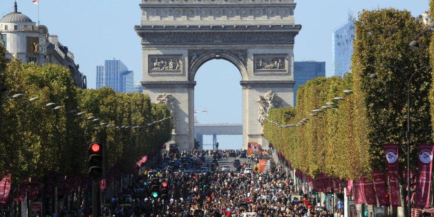 People walk on the Champs Elysees during the "day without cars", in Paris, France, Sunday, Sept. 27, 2015. Pretty but noisy Paris, its gracious Old World buildings blackened by exhaust fumes, is going car-less for a day. Paris Mayor Anne Hidalgo presided over Sunday's "day without cars," two months before the city hosts the global summit on climate change. (AP Photo/Thibault Camus)