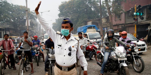 A traffic policeman wears a mask and controls traffic on a busy road in Mumbai, India, Tuesday, April 14, 2015. Air pollution