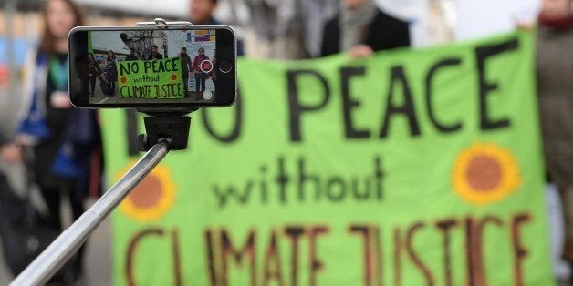 A person records with a selfie-stick a demonstration of activists of environmental organization Greenpeace at the venue of the COP21 United Nations climate change conference in Le Bourget, on the outskirts of Paris, on December 11, 2015.The COP21 was supposed to finish on December 11, but the final deal of the 195-nation conference on global warming was extended another day after ministers failed to bridge deep divides during a second consecutive all-night round of negotiations. / AFP / MIGUEL MEDINA (Photo credit should read MIGUEL MEDINA/AFP/Getty Images)