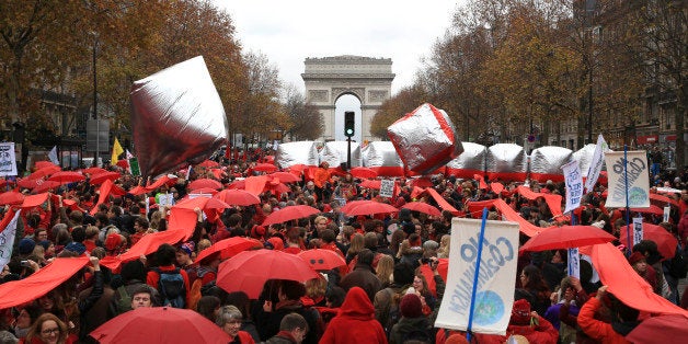 Climate activists demonstrate with red umbrellas in Paris, Saturday, Dec.12, 2015 during the COP21, the United Nations Climate Change Conference. Several environmental and human rights groups are planning protests around Paris to call attention to populations threatened by man-made global warming and urge an end to human use of oil, gas and coal. The Arc de Triomphe is seen in background. (AP Photo/Thibault Camus)