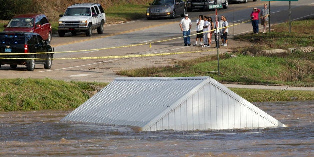 A building is submerged by the Pea river as people wait to cross in to downtown on highway 84 bridge, Dec. 26, 2015 in Elba, Ala. The river crested today and began to recede before flooding the downtown area. Officials said more than 100 houses and businesses were flooded by the rising waters. (AP Photo/ Hal Yeager)