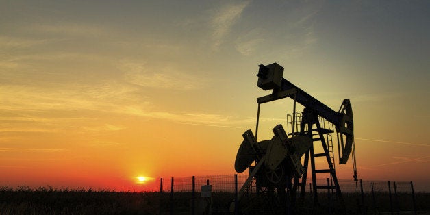 Operating oil and gas well profiled on sunset sky