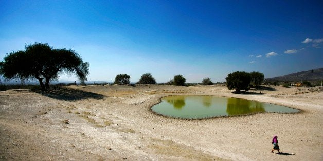 TEHUACAN, MEXICO - FEBRUARY 4: A Mexican woman skirts a Jaguey water hole, February 4, 2006 near San Marcos Tlacoyalco, Mexico. The Tehuacan Valley South-East of Mexico City has long experienced severe water shortages. Drought and climate change have contributed to this but recent industrial growth has also placed tremendous strain of a very limited ground water resource. Big industry has taxed this resource so severely that many small farmers and rural people have had no choice but to move closer to the cities and abandon their traditional lives. Water resources in the area area largely based on a weekly delivery by truck as well as collecting water from small pools known as Jagueys. This collected water was traditionally only used for animals but now more and more people are relying on it as a water source for crops and for drinking and bathing purposes. (Photo by Brent Stirton/Getty Images)