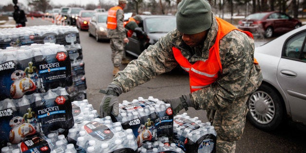 FLINT, MI - JANUARY 21: Army National Guard Specialist David Brown loads bottled water into waiting cars at a fire station on January 21, 2016 in Flint, Michigan. Residents can go daily to fire stations in the city to pick up more water. (Photo by Sarah Rice/Getty Images)