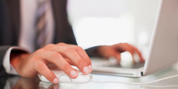 Businessman using computer mouse and typing on laptop