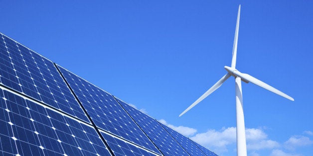 Solar panels and wind turbine against blue sky