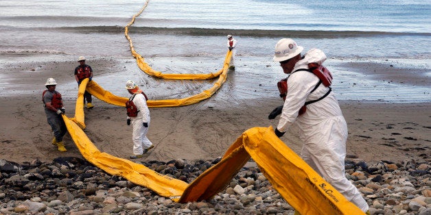 FILE - In this May 21, 2015, file photo, workers prepare an oil containment boom at Refugio State Beach, north of Goleta, Calif., two days after a ruptured pipeline created the largest coastal oil spill in California in 25 years. Exxon Mobil Corp. won approval Monday, Feb. 1, 2016, for its plan to use trucks to move more than 17 million gallons of oil stranded in storage tanks after the spill, despite concerns from an environmental group that highway safety could be jeopardized. (AP Photo/Jae C. Hong, File)