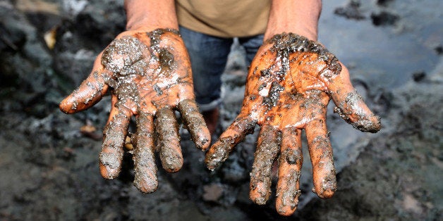 Eric Dooh, a farmer, shows the oil polluted mud from his fish ponds affected by an oil spill in 2004 in Goi, Nigeria, on Wednesday, Jan. 13, 2016. Twenty years after the oil-pollution crisis in the Niger delta shot to world attention when the then military government hanged the author and environmentalist, Ken Saro-Wiwa, residents in the region are seething with anger again that the problem hasnt been fixed. Photographer: George Osodi/Bloomberg via Getty Images