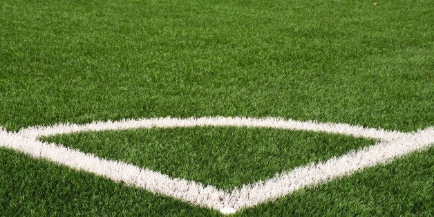 Football playground corner on heated artificial green turf ground with painted white line marks. Milled black rubber in basic