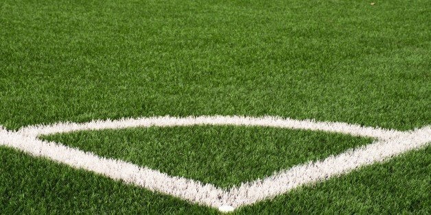 Football playground corner on heated artificial green turf ground with painted white line marks. Milled black rubber in basic of ground.