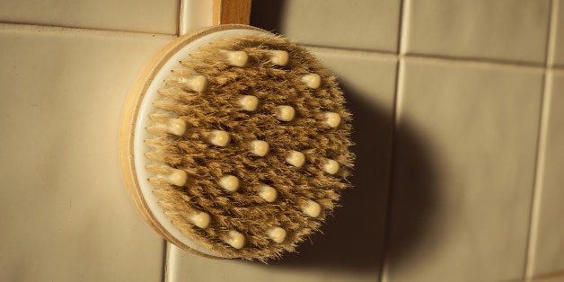 Shower brush in the bathroom against a tiled wall in the morning sunlight