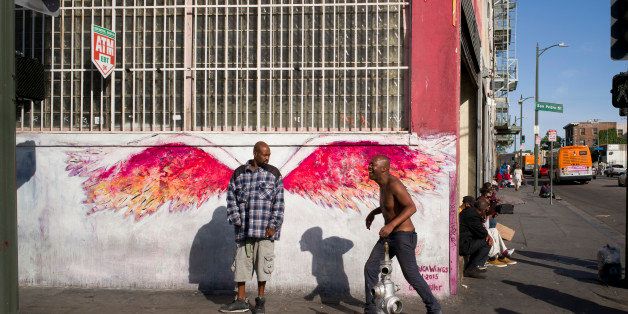 FILE - In this Monday, April 25, 2016 file photo, a man stands in front of angel wings painted by artist Colette Miller on Skid Row in downtown Los Angeles. The number of homeless people in Los Angeles County increased 5.7 percent over the past year, to report released Wednesday, May 4, 2016, but homelessness among veterans and families fell significantly. (AP Photo/Jae C. Hong, File)
