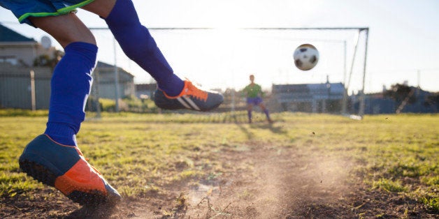 Close up action of boy, aged 14, taking a penalty kick in a football match